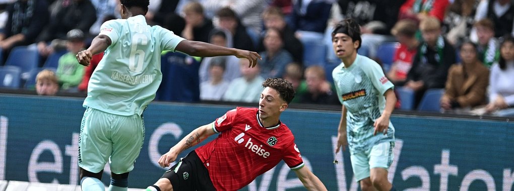 Voller Einsatz: Hannovers Jannik Rochelt (M) im Zweikampf mit Kaiserslauterns Almamy Toure (l) - © Carmen Jaspersen/dpa