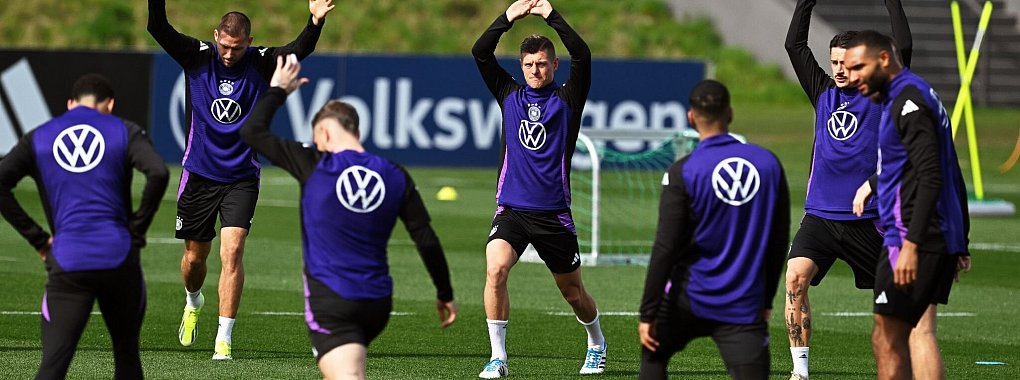 Die deutschen Nationalspieler führen im Training Dehnübungen durch. - © Arne Dedert/dpa