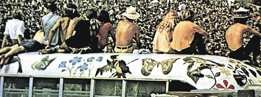 Woodstock-Festivalbesucher haben das Dach eines der bemalten ehemaligen Schulbusse der &bdquo;Hog Farm&ldquo;-Kommune erklommen. - &copy; imago images