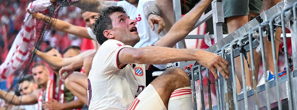 Thomas Müller steigt nach dem Bayern-Sieg auf den Zaun zu den Fans. - © Sven Hoppe/dpa