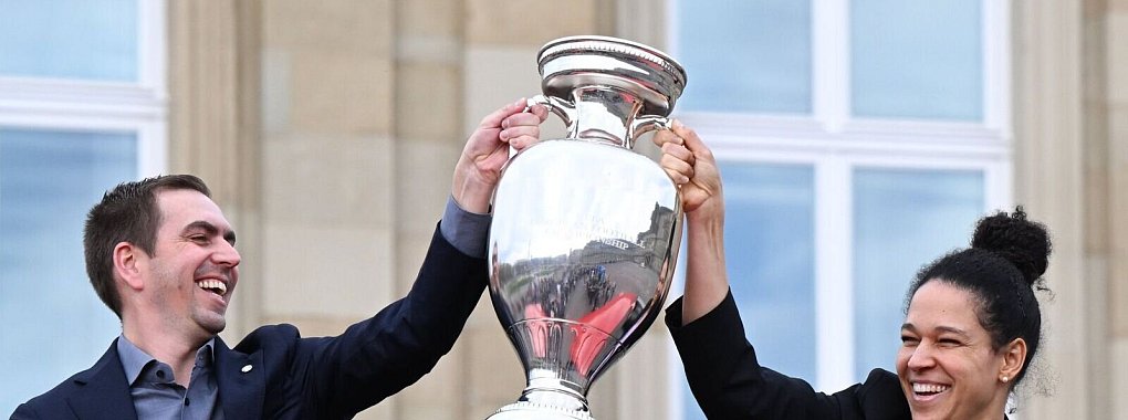 Philipp Lahm, Turnierdirektor der Fußball-Europameisterschaft, hält zusammen mit der früheren Fußball Nationalspielerin Celia Sasic den EM-Pokal hoch. - © Bernd Weißbrod/dpa