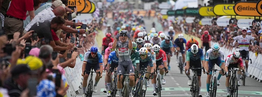 Der Belgier Jasper Philipsen jubelt beim &Uuml;berqueren der Ziellinie vor dem Deutschen Pascal Ackermann (l), dem Kolumbianer Fernado Gavira (2.v.l). - &copy; Daniel Cole/AP/dpa