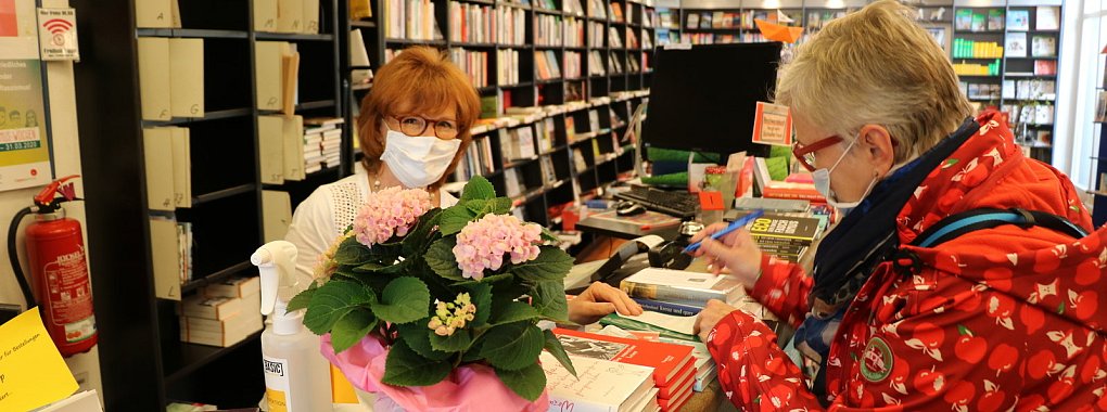 Elke Lange (links) kann wieder Bücher über die Ladentheke reichen. Sie und Kundin Petra Schröder-Heidrich halten sich an die Empfehlung eine Maske in Geschäften zu tragen. - © Till Sadlowski