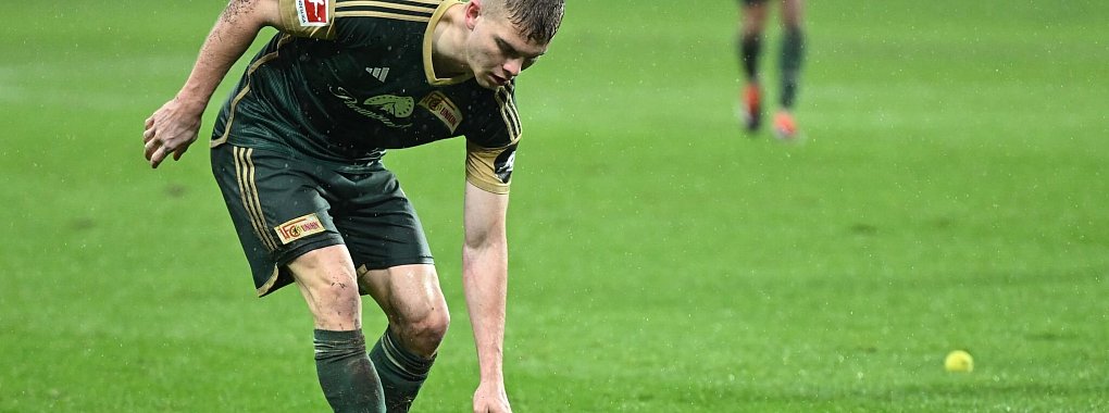 Andras Sch&auml;fer von Union hebt einen Tennisball auf, der aus dem Block der Union-Fans geworfen wurde. - &copy; Arne Dedert/dpa