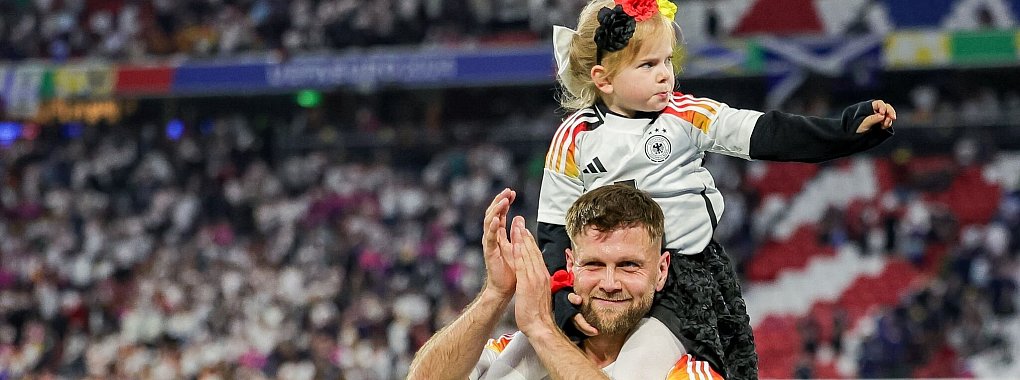 Niclas F&uuml;llkrug tr&auml;gt nach dem ersten EM-Spiel der Deutschen seine Tochter Emilia durch das Stadion. - &copy; Christian Charisius/dpa