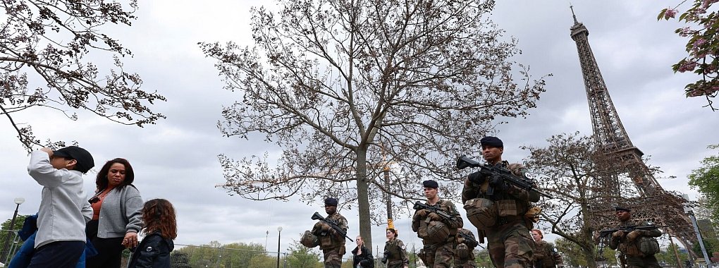 Soldaten patrouillieren entlang einer Baustelle für die bevorstehenden Olympischen Spiele in den Trocadero-Gärten gegenüber des Eiffelturms. - © Aurelien Morissard/AP/dpa