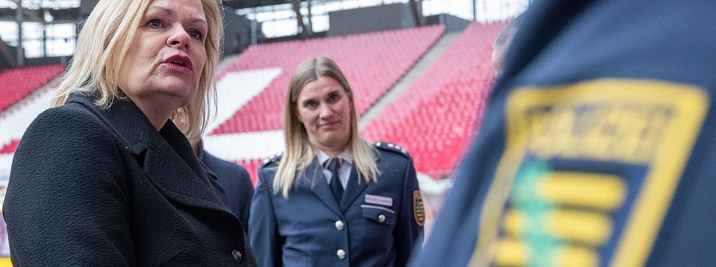 Nancy Faeser (SPD, l), Bundesinnenministerin, unterh&auml;lt sich in der Leipziger Arena mit Vertretern der Polizei. - &copy; Hendrik Schmidt/dpa