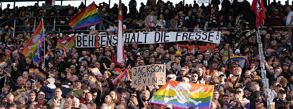 Fans des FC St. Pauli protestieren mit drastischen Worten gegen die umstrittenen Aussagen von Wolfsburgs Kevin Behrens. - © Marcus Brandt/dpa