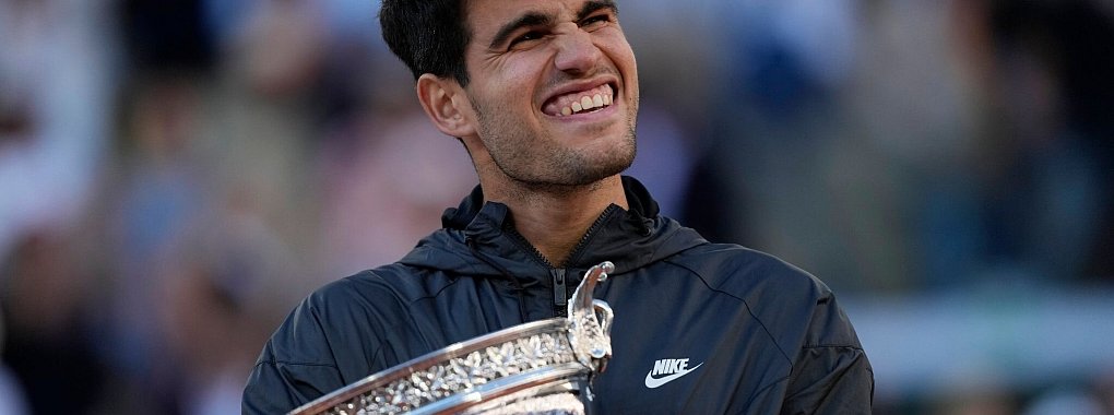 Carlos Alcaraz feiert mit der Troph&auml;e nach seinem Sieg. - &copy; Thibault Camus/AP
