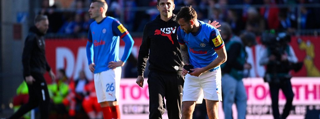 Kiels Trainer Marcel Rapp umarmt Marco Komenda nach der 0:3-Niederlage auf dem Rasen. - © Gregor Fischer/dpa