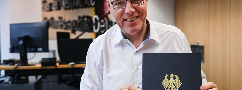 Der Präsident des Hauses der Geschichte, Harald Biermann, zeigt die Mappe mit der «Zeitenwende»-Rede von Olaf Scholz. - © Oliver Berg/dpa