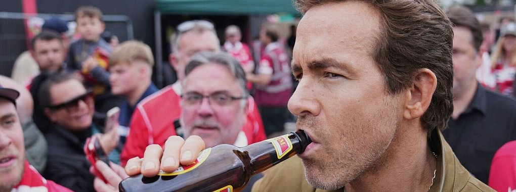 Schauspieler Ryan Reynolds lässt sich vor dem Spiel seines Clubs AFC Wrexham ein Bier schmecken. - © Jon Super/AP/dpa