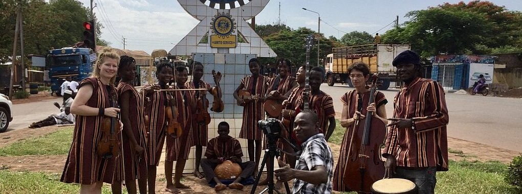 Das Ensemble der Musikschule Ouagadougou beim Video-Clip-Dreh in Bobo-Dioulasso - vor dem Rotary-Wappen. Rotary ist ein Sponsor der Schule. Ganz links im Bild: Maria Behrens. - &copy; Bildrechte: Maria Behrens