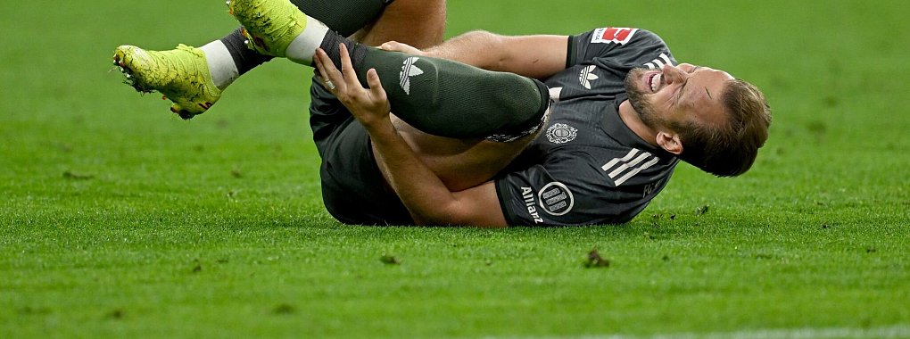 Bayern-Stürmer Harry Kane hält sich nach einem Zweikampf den Knöchel. - © Sven Hoppe/dpa