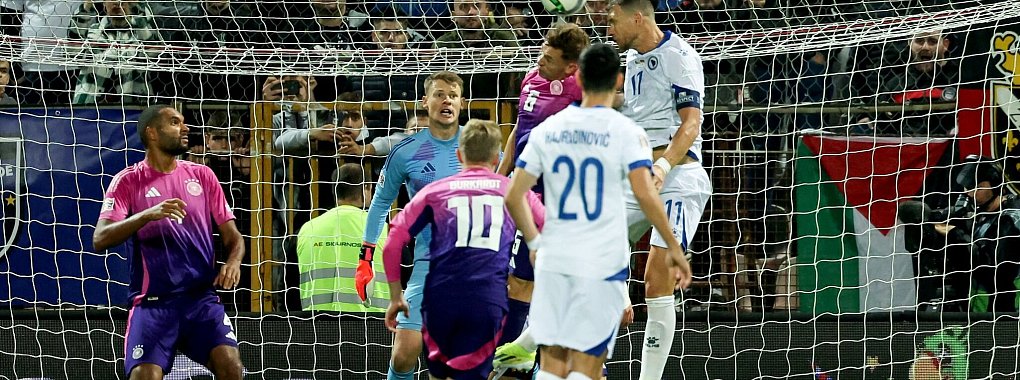 Bosniens baumlanger Angreifer Edin Dzeko (r) ist höher in der Luft als Joshua Kimmich und überwindet per Kopf Torwart Alexander Nübel. - © Christian Charisius/dpa