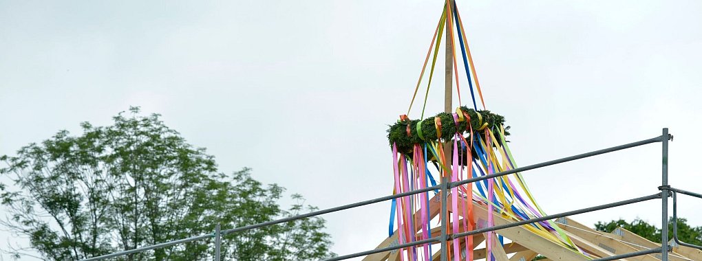 Richtkranz auf einem neu gebautem Haus. Richtfest auf einer Lückenbebauung. An einem neu gebauten Wohnhaus im Speckgürtel von Leipzig hängt ein Richtkranz im rohbaufertigen Dachstuhl. - © Volkmar Heinz/dpa-Zentralbild/dpa-tmn