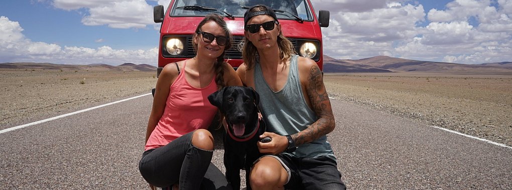 Auf den Straßen Südamerikas unterwegs: Karolina und Fabian Weinfurtner mit Labradorrüde Myliu. Im Hintergrund: ihr roter "Tornado", ein vollständig umgebauter VW-Bulli aus dem Jahr 1988. - © Bildrechte: Karolina und Fabian Weinfurtner