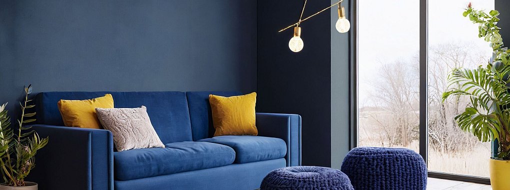 Mut zur Farbe: Dunkelblaue Wände und ein passendes Sofa schaffen eine gemütliche Atmosphäre und laden zum Entspannen ein. - © Erismann/DTI/dpa-tmn