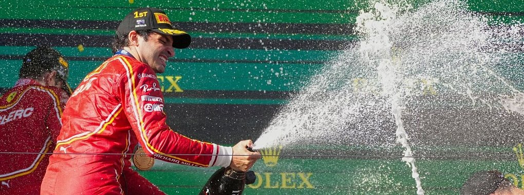 Ferrari-Pilot Carlos Sainz feiert mit Champagner seinen Sieg. - © Scott Barbour/AP/dpa