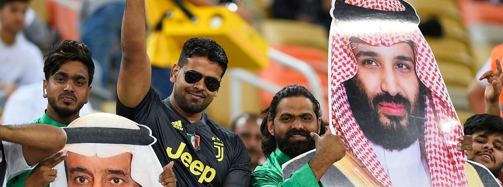 Saudische Fußballfans finden die Sport-Strategie des Königreichs um Kronprinz Mohammed bin Salman (auf dem rechten Plakat) gut. - © ---/AP/dpa