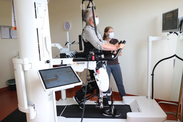 Inka Siekmeier läuft im Gangroboter, ihre Ergotherapeutin Karin Fischer steht neben ihr. - © Alexandra Schaller