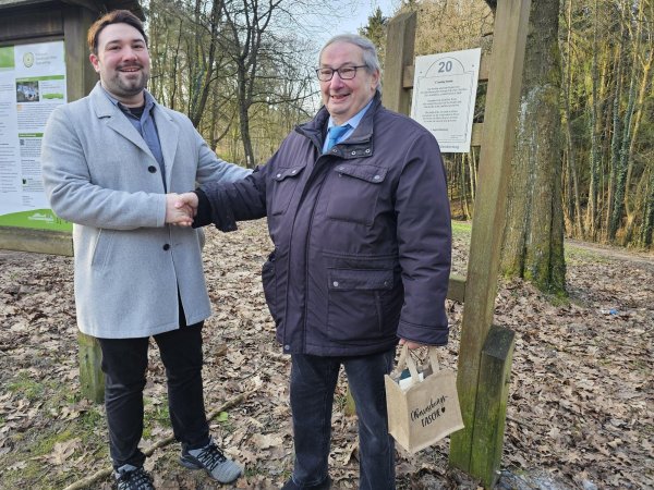 Lucas Noke, Leiter des Tourismus-Büros der Stadt Lage, bedankt sich bei Bernd Rosarius. Der hat die Autorengruppe "Garten der Poesie" gegründet und gibt seit Jahrzehnten Autorinnen und Autoren ein Forum. Am Wanderweg in Hörste stehen zum Beispiel Gedichte. - © Astrid Sewing