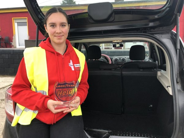 Jana Diser zeigt steht an ihrem Auto, in der Hand hält sie die Auszeichnung als „Heldin der Straße", die sie für ihren Einsatz im vergangenen Juni bekommen hat. - © Sven Kienscherf