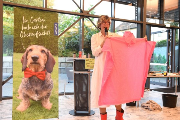 Katrin Iskam hat unterschiedliche Utensilien dabei, die sie in ihrem Garten-Programm humorvoll einbindet. Unter anderem einen rosafarbenen Regenponcho. Immer mit dabei ist Chefgärtner Rauhaardackel Tyson. - © Karin Prignitz