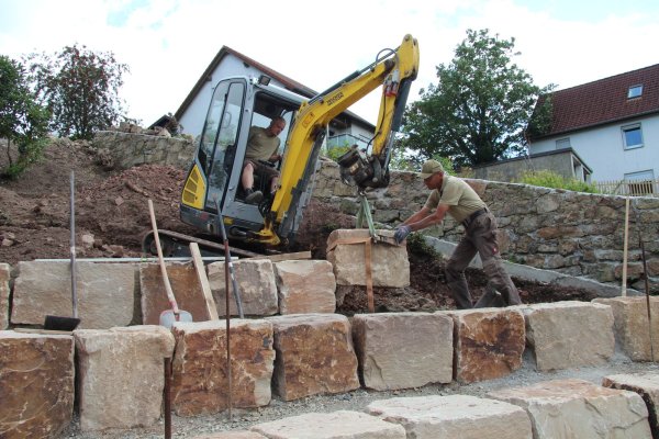 Marius-Alexander Engelking (links) und Ulrich Reineke setzen einen der letzten Steine für das neue Amphitheater in Talle. - © Nadine Uphoff