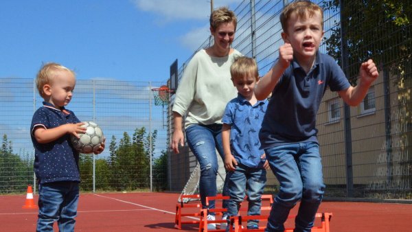 Aus dem LZ-Archiv: Eine Szene von der Einweihung des Leopoldshöher Kunstrasens 2022, beispielhaft für den hohen Wert des Vereinslebens in Lippe. Zuschauer Liam (von links), Mama Nicole mit Luca (3) und Levi (5) hüpfen im Schlusssprung über kleine Hürden - eine Übung aus dem Anfängertraining der Handballer. - © Archivfoto: Sibylle Kemna