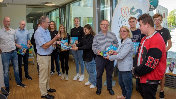 IHK-Vizepräsident Alfred W. Westermann (5. von rechts) überreicht das erste Exemplar des Ausbilungsatlasses 2023/2024 an Brigitta Wulf, Leiterin der Johannes-Gigas-Sekundarschule in Lügde. Mit im Bild: Tobias Haak (2. von links, passgenaue Besetzung von Ausbildungsplätzen) und IHK-Bildungsgeschäftsführer Michael Wennemann (4. von links). - © YT