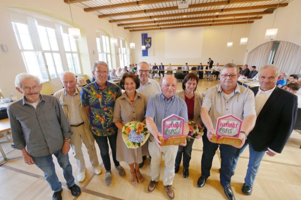 Vor der Ratssitzung verleiht Bürgermeister Heinz-Dieter Krüger (rechts) die Heimatpreise, deren Gewinner er schon Ende 2022 im Rat verkündet hatte. Es habe Lieferschwierigkeiten bei den Trophäen gegeben. Dafür kann die Stadt nichts, aber es passte perfekt ins Bild der konfusen Ratssitzung voller Pleiten und Pannen. - © Jost Wolf
