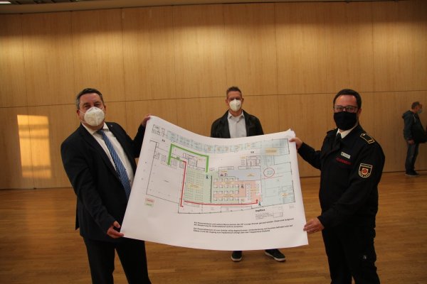 Landrat Dr. Axel Lehmann (links) und Sascha Medina vom Bevölkerungsschutz des Kreises Lippe (rechts) zeigen den Plan für das Impfzentrum im Kongressbereich der Phoenix Contact Arena. Dahinter ist Dr. Christian Körner, Leiter der Bezirksstelle Detmold der Kassenärztlichen Vereinigung Westfalen-Lippe zu sehen. - © Jana Beckmann