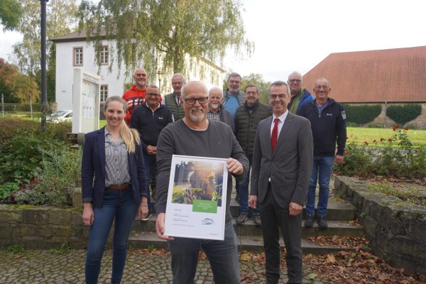 Bürgermeister Jörg Bierwirth (vorne rechts) übergibt gemeinsam mit Westenergie-Kommunalmanagerin Maria Kemker die Urkunde an Dirk Steinmeier, Sprecher der LTG. Darüber freuen sich auch die weiteren Mitglieder der Gruppe: Uli Göke (hinten von links), Oliver Bruns, Uwe von Glembotzki, Fritz Loke, Dieter Vogel, Klaus Föste, Jürgen Koch und Dirk Vogel. - © Michaela Weiße