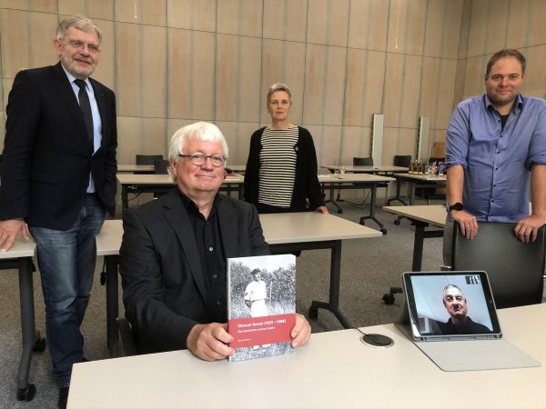 Aus Israel ist mit Michael Raveh (unten rechts auf dem Tablet) der Sohn von Shmuel und Ehrenbürgerin Karla Raveh zugeschaltet. Für seine Buchveröffentlichung zeigen sich im Ratssaal (von links) Bürgermeister Dr. Reiner Austermann, der frühere Museumsleiter Jürgen Scheffler, Kultur-Geschäftsbereichsleiterin Annette Paschke-Lehmann und Museums-Chef Fabian Schröder dankbar. - © Till Brand