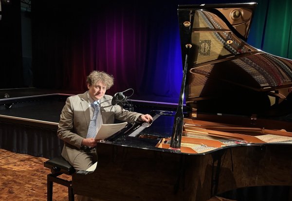 Sebastian Krämer bei der Hörbuch-Lesung: „Ein Licht geht uns auf…“ im Forum der Karla-Raveh-Gesamtschule Lemgo am Klavier. - © Tamina-Shirin Marten