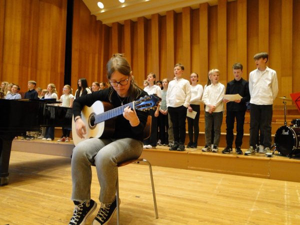 Überraschungsgast Carla Peters aus der Klasse 9c begleitet den Chor "Rudolphis" an der Gitarre. Das war im Programm nicht ausgewiesen und sollte das i-Tüpfelchen auf dem Liedervortrag des Unterstufenchores werden. - © Hajo Gärtner