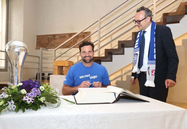 TBV-Trainer Florian Kehrmann trägt sich ins Goldene Buch ein, Bürgermeister Markus Baier schaut ihm dabei über die Schulter. - © TBV lemgo Lippe/Paul Cohen