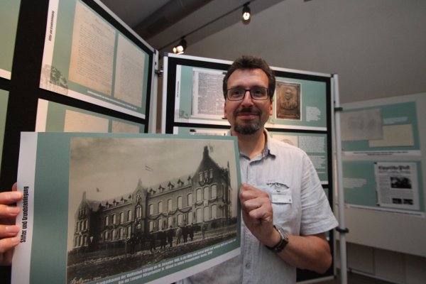 Stadtarchivar Marcel Oeben zeigt ein Foto von der Eröffnung des Lemgoer Krankenhauses im Jahr 1900, das in der Ausstellung im Hexenbürgermeisterhaus zu sehen ist. - © Jens Rademacher