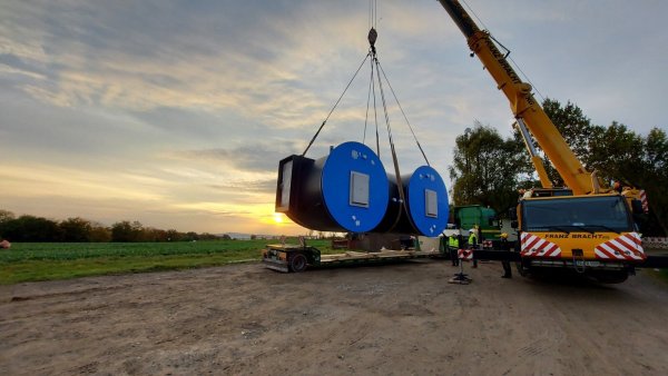 Ein Teil des neuen Hochbehälters wird vom Lkw mit einem Kran auf den Anhänger eines Treckers umgeladen. - © Stadtwerke Lemgo