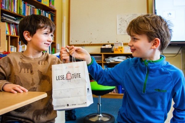 Erstklässler Michel (6, links) bekommt von seinem Lesepaten Maxi (10) aus der 4c eine selbst bemalte Lesetüte überreicht. - © Raphael Bartling