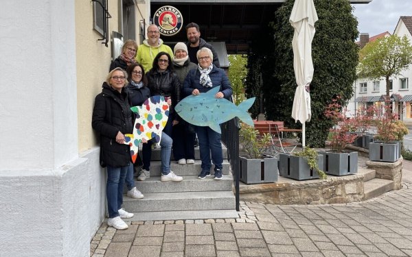 Maike Trompeter (von links), Angela Schirmag, Birgit Wiegrebe, Nicole Reineke, Björn Strohmeier, Manuela Blome, Johann Falk und Steffi Grönke haben zur Einstimmung bunte Holzfische in der Stadt aufgehängt, die von Schülerinnen und Schülern des Gymnasiums Barntrup hergestellt wurden. - © Marketingverein