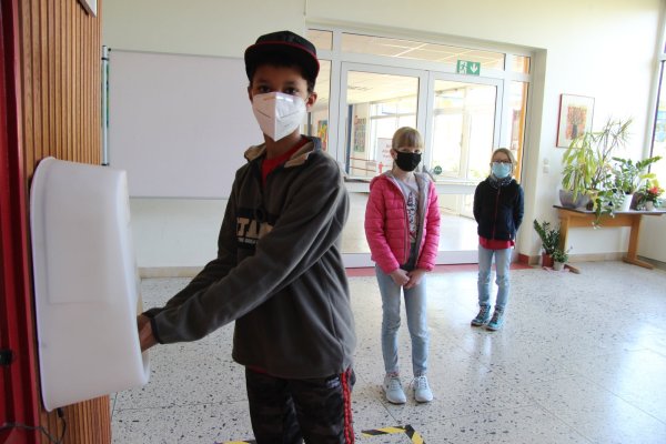 Jeremy desinfiziert sich die Hände, während Wiktoria (links) und Helen warten, bis sie an der Reihe sind. - © Kirsten Fuhrmann