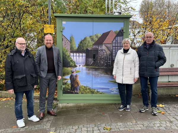 Künstler Harald Hoffmann, Stadtwerke-Geschäftsführer Volker Stammer sowie die Vereinsmitglieder Monika Kramer und Rainer Laag präsentieren das Motiv „Heerser Mühle“ auf einer Gas-Station. - © Stadtwerke Bad Salzuflen