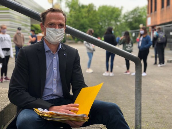 Schulleiter Oliver Dudek sitzt mit Maske auf dem Schulhof der Gesamtschule Aspe.  - © Sven Kienscherf