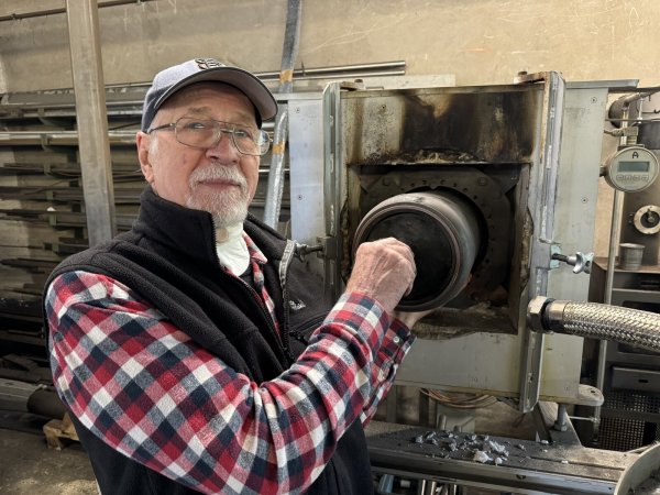 Hilmar Hubbes zeigt, wie die runde Retorte in den Müllvermeidungs-Ofen geschoben wird. - © Sandra Castrup