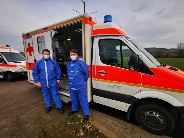 Bastian Wieneke (Rettungsassistent) und Daniel Wurms (Rettungssanitäter) vom Deutschen Roten Kreuz aus Leopoldshöhe sind für den Transport eines COVID-19 infizierten Patienten gerüstet. - © Freitag TV