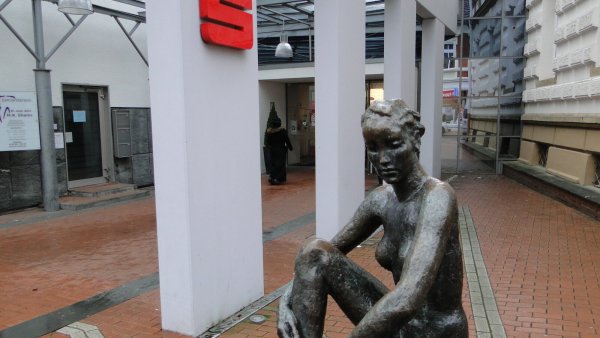 Seit 1929 bewacht „Die große Sitzende", eine etwaein Meter große Bronzeskulptur des Künstlers Georg Kolbe (1877-1947), den Eingang zur Sparkasse. - © Hajo Gärtner