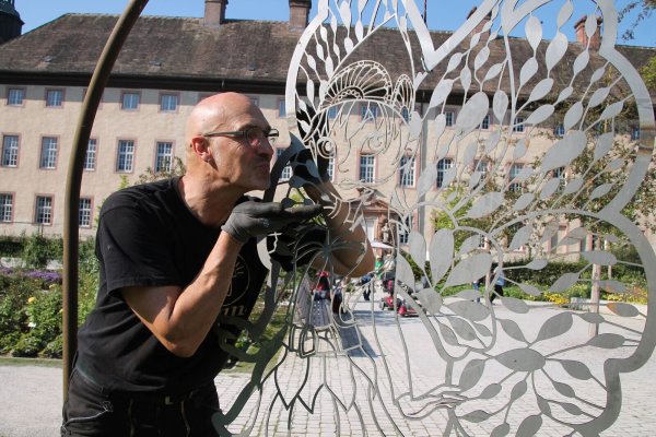 Ein Küsschen für Holli: Künstler Hans Kordes hat eine stählerne Version der geflügelten Gartenschau-Botschafterin geschaffen. Im Remtergarten soll die Skulptur beim Event "Höxter leuchtet" zu Selfies einladen. - © LGS Höxter/Manuela Puls