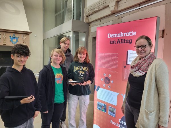 Fabian Perez (MWG), R. Ollenburg (EKG), Vincent Andermann (MWG), Merle Brakemeier (EKG) und Dr. Sonja Girod (VHS Lemgo, von links) haben zusammen eine Ausstellung mit Führung in der VHS Lemgo unter dem Titel „Demokratie stärken – Rechtsextremismus bekämpfen" erarbeitet. - © Freya Köhring